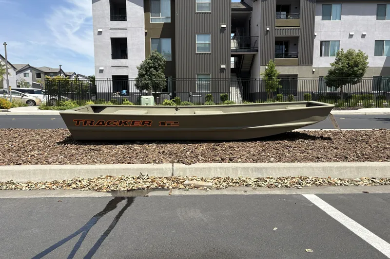 The Image of 2026 Tracker Grizzly 12 Jon boat displayed outdoors near modern apartments. - 0