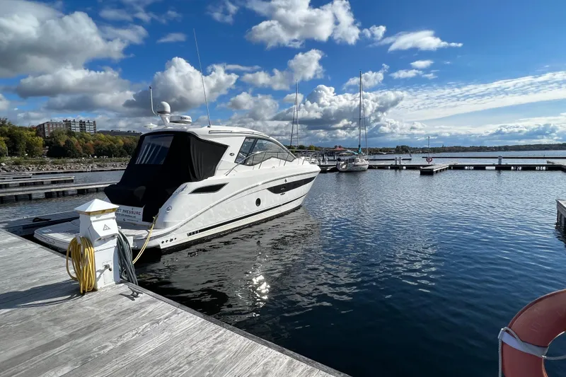 The Image of 2021 Sea Ray Sundancer 350 Coupe docked at a marina under a blue sky. - 0