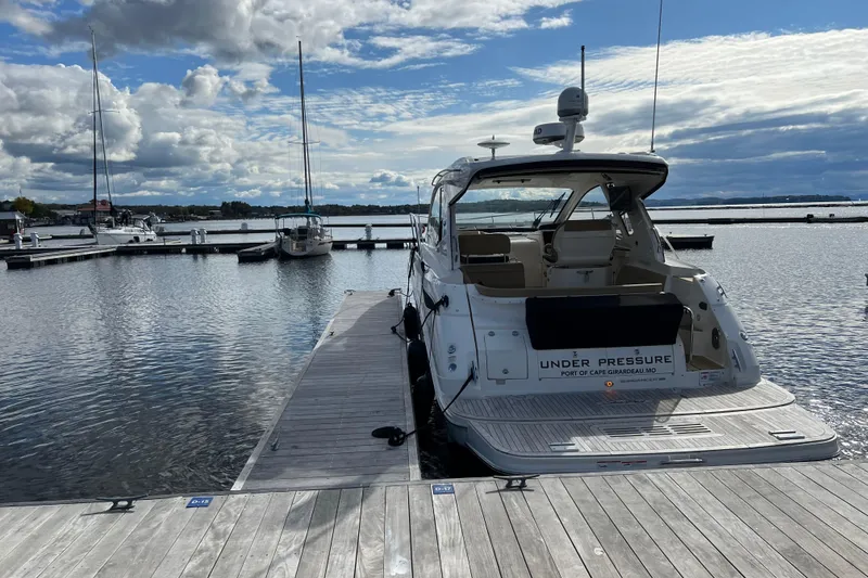 Slide: The Image of 2021 Sea Ray Sundancer 350 Coupe docked at a marina under cloudy skies. - 1