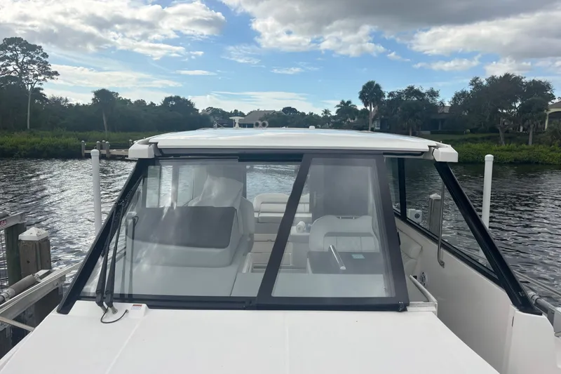 Slide: The Image of 2024 Regal 36 XO boat docked on a serene river with lush greenery. - 14