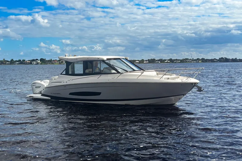 Slide: The Image of 2024 Regal 36 XO boat cruising on a calm lake under a partly cloudy sky. - 4