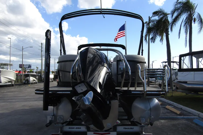 Slide: The Image of 2022 Starcraft SLS 5 boat with outboard motor, parked near palm trees and American flag. - 5