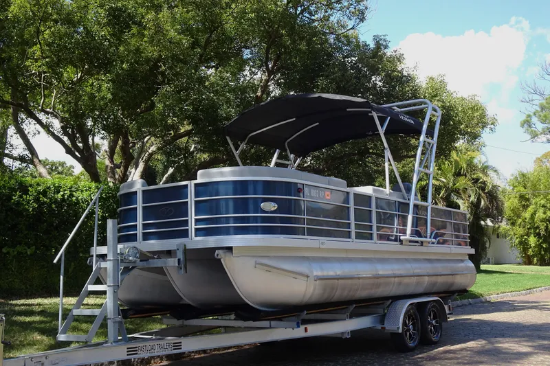 Slide: The Image of 2018 Veranda VF22TT pontoon boat on trailer, parked under trees. - 7