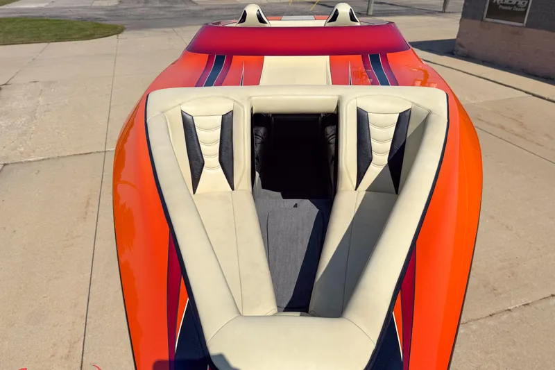 Slide: The Image of 2012 DCB 28 Extreme boat with vibrant orange and white seating on a concrete surface. - 13