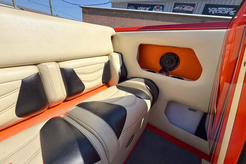 Slide: The Image of 2012 DCB 28 Extreme boat interior with beige and black seating, speaker, and orange accents. - 16