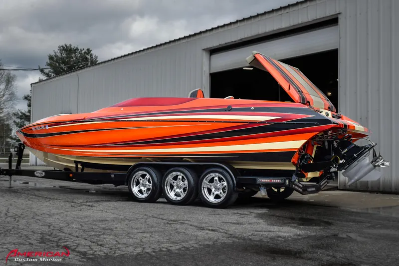 Slide: The Image of 2012 DCB 28 Extreme speedboat with vibrant orange and black design on a trailer. - 2