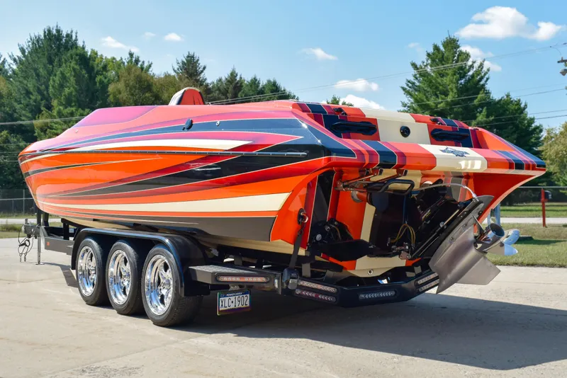 Slide: The Image of 2012 DCB 28 Extreme boat with vibrant orange and red design on a triple-axle trailer. - 3