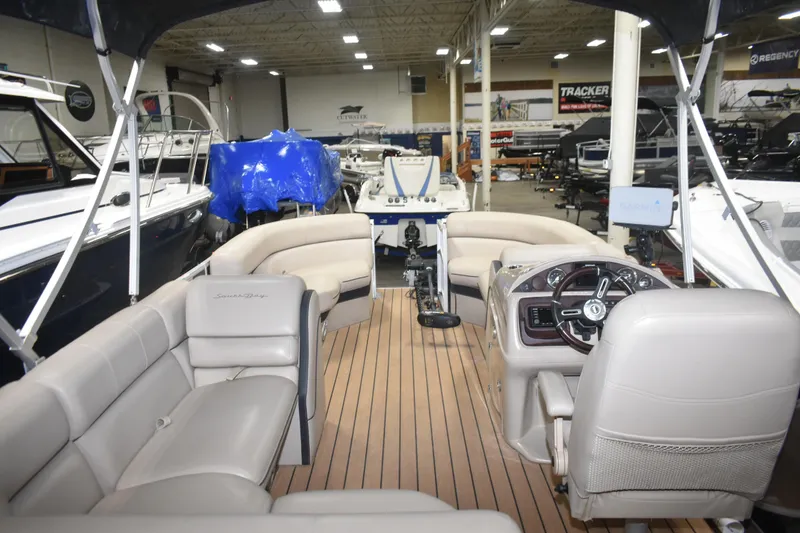 Slide: The Image of 2019 South Bay 523FCR pontoon boat interior with beige seating and wood flooring. - 16