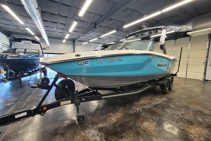 Slide: The Image of 2024 MasterCraft NXT24 boat in showroom, blue hull, on trailer. - 10