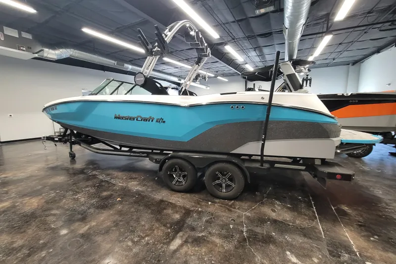 Slide: The Image of 2024 MasterCraft NXT24 boat in showroom, blue and gray design on trailer. - 13