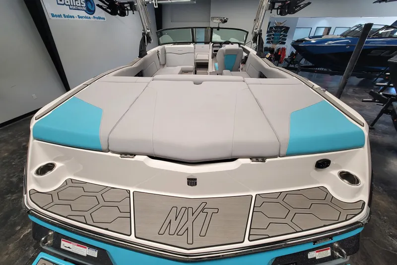 Slide: The Image of 2024 MasterCraft NXT24 boat interior with gray and blue seating, displayed in showroom. - 17