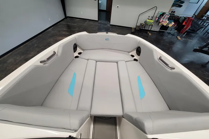 Slide: The Image of 2024 MasterCraft NXT24 boat interior with gray and blue seating in showroom. - 22