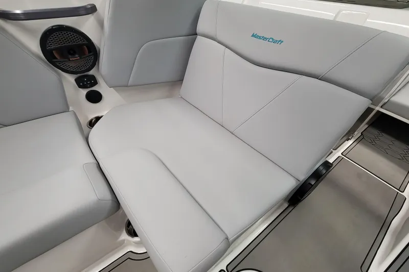 Slide: The Image of 2024 MasterCraft NXT24 boat interior with gray seating and speaker system. - 23