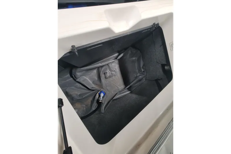 Slide: The Image of 2024 MasterCraft NXT24 storage compartment with black interior and visible fittings. - 28