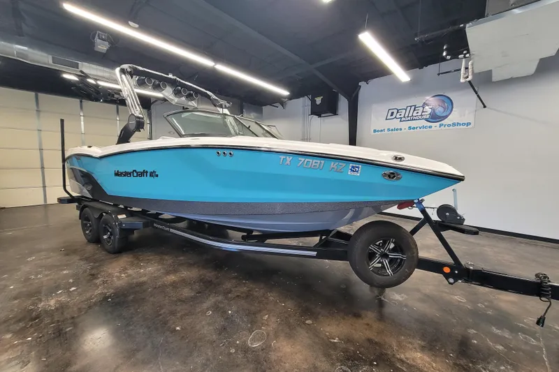 The Image of 2024 MasterCraft NXT24 boat in showroom, blue hull, on trailer, Dallas Boathouse. - 7