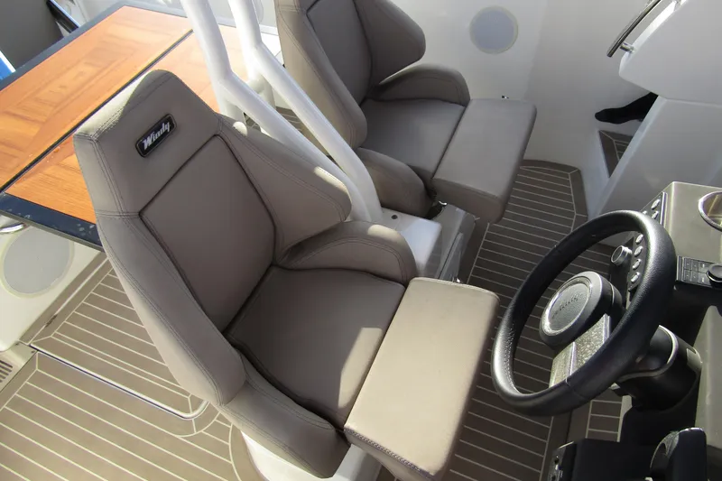 Slide: The Image of 2023 Windy SR28 CC boat interior with steering wheel and cushioned seats. - 10