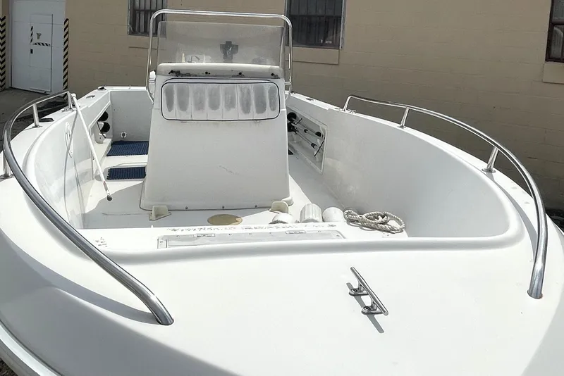 Slide: The Image of 1996 PROLINE 19 boat with white deck and railing, docked near a building. - 3