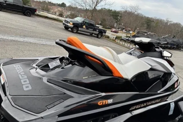 Slide: The Image of 2013 Sea-Doo GTI SE 130 jet ski in a parking lot, black and orange design. - 2