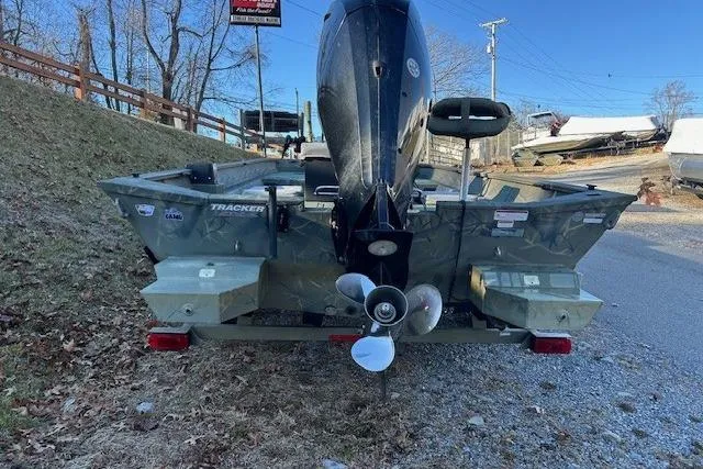 Slide: The Image of 2016 Tracker Grizzly 2072 MVX CC boat, rear view with motor, parked on gravel. - 11