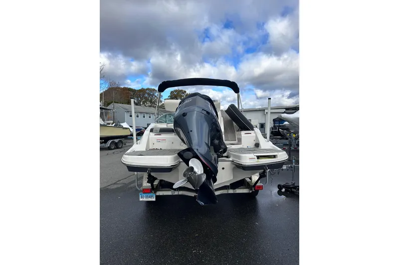 Slide: The Image of 2020 Regal 21 OBX boat with outboard motor, parked on a trailer under cloudy skies. - 5