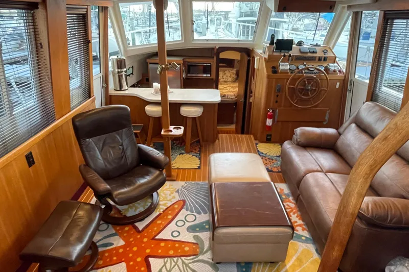 Slide: The Image of Interior of 2003 Mainship 430 Trawler with leather seating and nautical decor. - 14