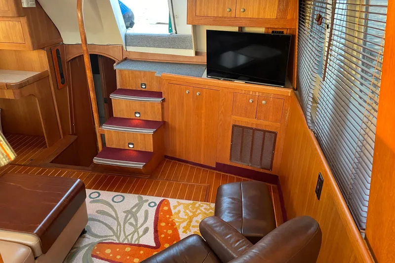 Slide: The Image of Interior of 2003 Mainship 430 Trawler with wooden cabinetry, TV, and leather seating. - 17