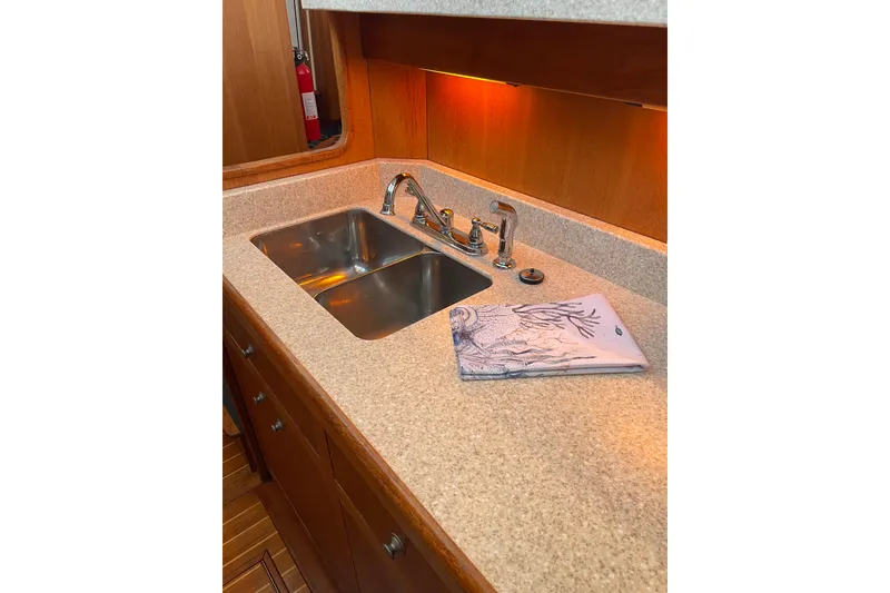 Slide: The Image of 2003 Mainship 430 Trawler kitchen sink with dual basins and decorative towel. - 26