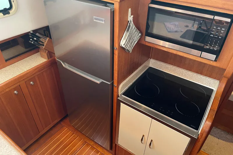 Slide: The Image of 2003 Mainship 430 Trawler kitchen with fridge, microwave, and electric stove. - 27