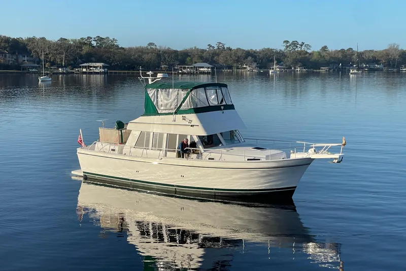 Slide: The Image of 2003 Mainship 430 Trawler on calm water, scenic background, clear sky. - 3