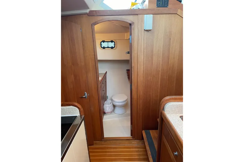 Slide: The Image of Interior of 2003 Mainship 430 Trawler, featuring a wooden bathroom door and compact toilet. - 31