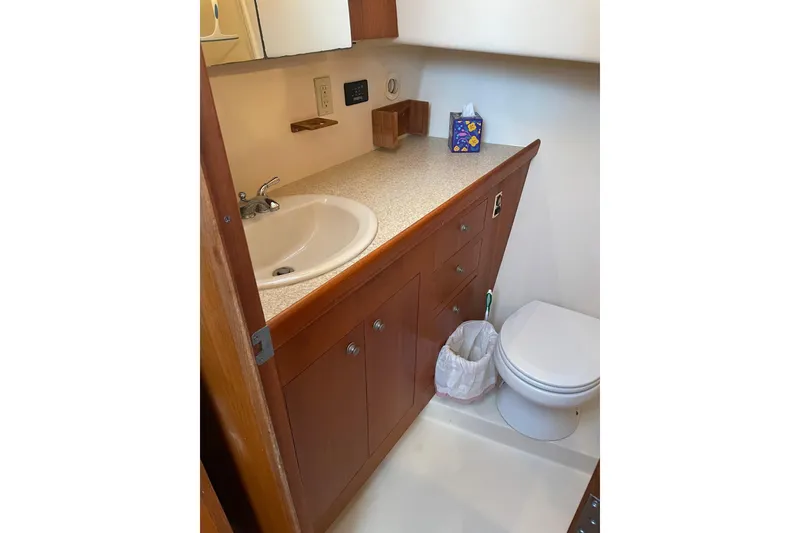 Slide: The Image of 2003 Mainship 430 Trawler bathroom with sink, toilet, and wooden cabinetry. - 32