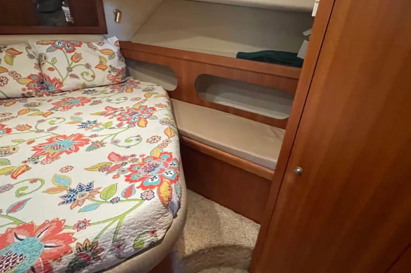 Slide: The Image of Cozy cabin interior of 2003 Mainship 430 Trawler with floral bedding and wooden storage. - 34