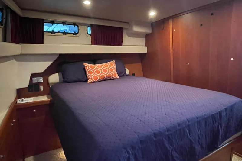 Slide: The Image of Cozy bedroom in 2003 Mainship 430 Trawler with wood paneling and nautical decor. - 37