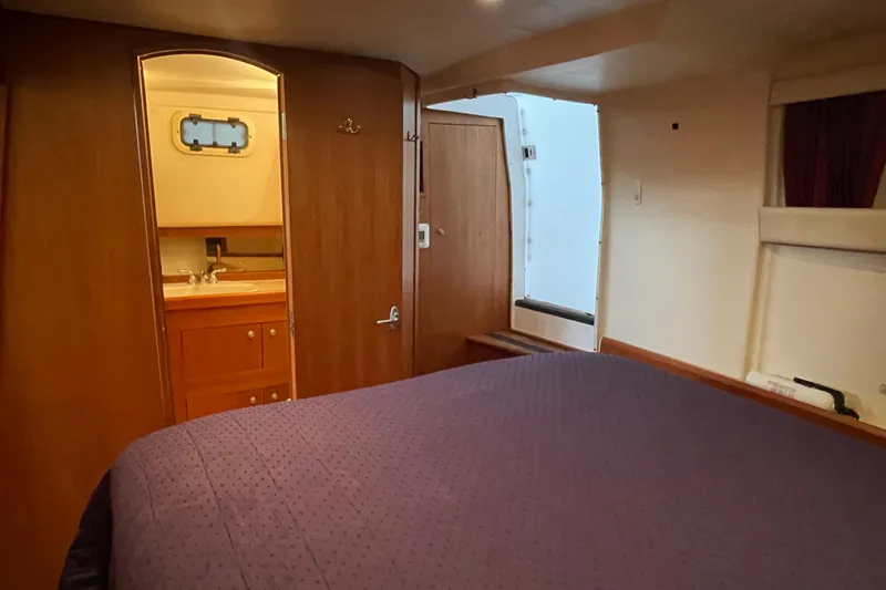 Slide: The Image of 2003 Mainship 430 Trawler cabin interior with bed, wooden cabinetry, and bathroom entrance. - 38