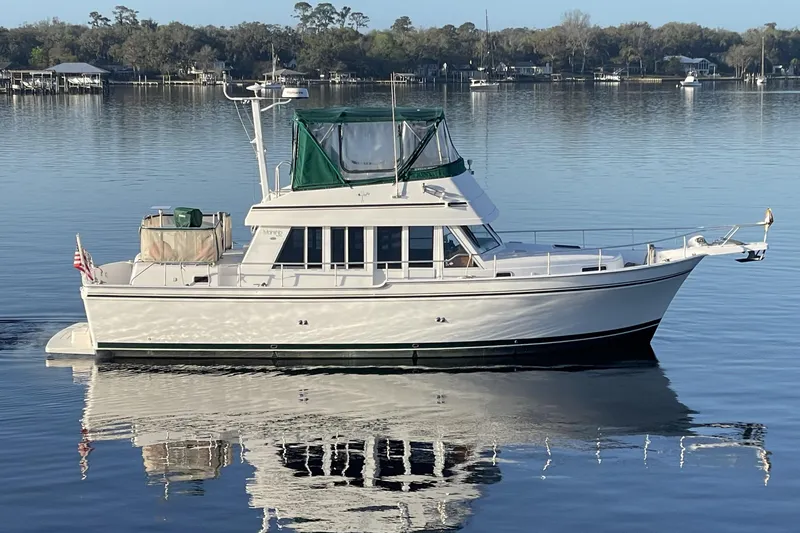 Slide: The Image of 2003 Mainship 430 Trawler on calm water, featuring green canopy and classic design. - 4