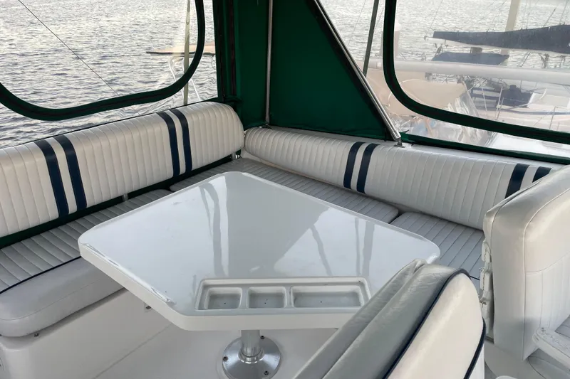 Slide: The Image of 2003 Mainship 430 Trawler interior with white seating and table, overlooking water. - 44