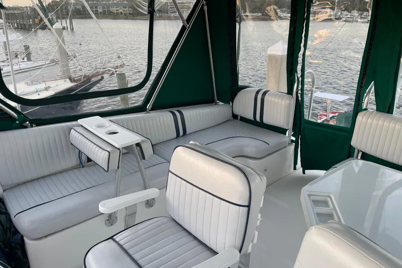 Slide: The Image of 2003 Mainship 430 Trawler interior with white seating, green canopy, and waterfront view. - 45