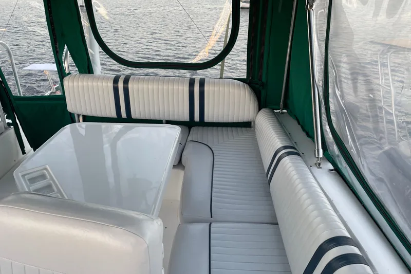 Slide: The Image of 2003 Mainship 430 Trawler interior with white seating and table, overlooking water. - 47