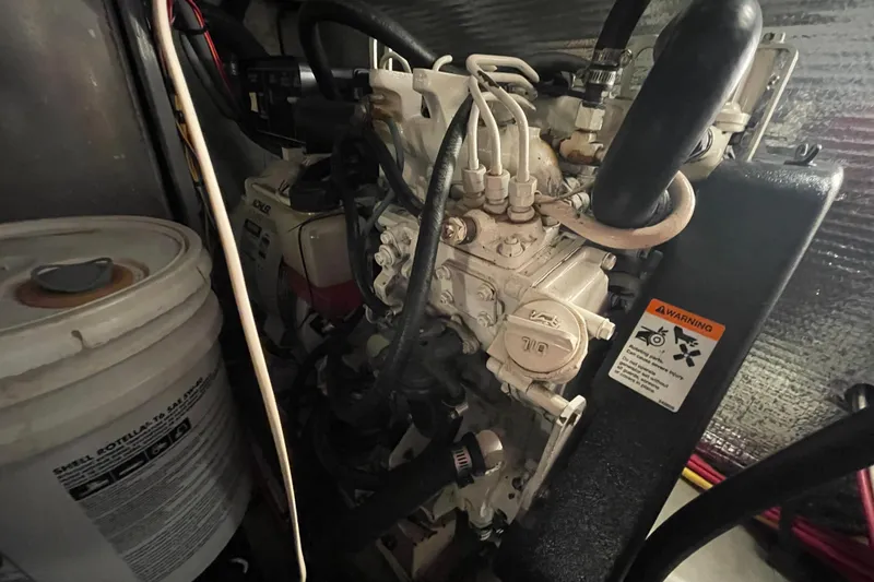 Slide: The Image of Engine compartment of a 2003 Mainship 430 Trawler with visible components and warning label. - 62