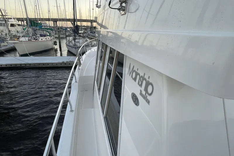 Slide: The Image of 2003 Mainship 430 Trawler docked at marina with sailboats in background. - 7
