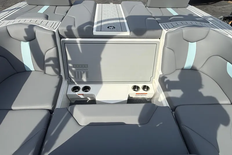 Slide: The Image of 2026 MasterCraft XT24 boat interior with gray and blue seating, cup holders, and storage compartment. - 10