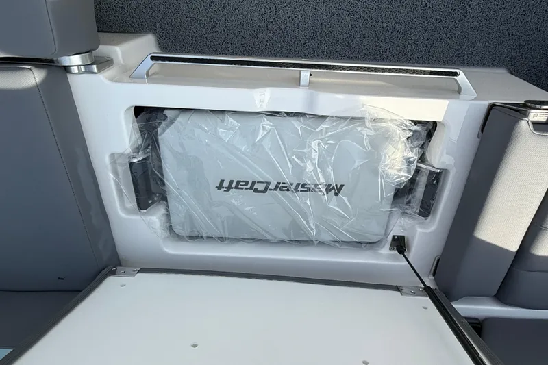 Slide: The Image of 2026 MasterCraft XT24 boat storage compartment with protective cover. - 11
