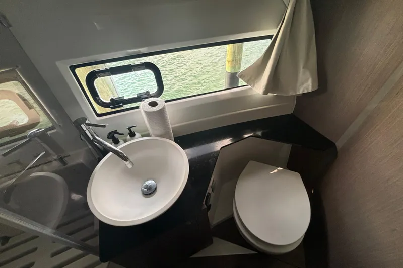 Slide: The Image of 2024 Jeanneau NC Weekender 1095 Fly bathroom with sink, toilet, and window view. - 18