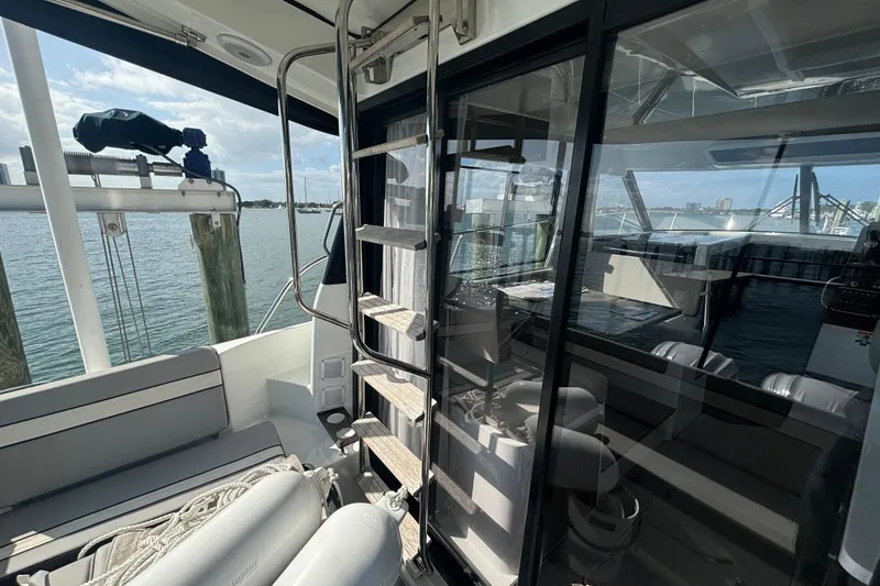 Slide: The Image of 2024 Jeanneau NC Weekender 1095 Fly, interior view with ladder and seating, docked by water. - 7