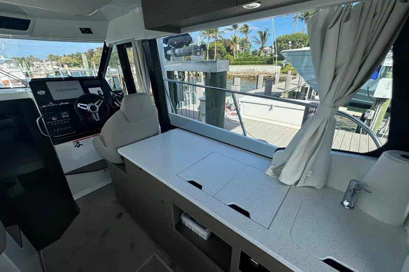Slide: The Image of 2024 Jeanneau NC Weekender 1095 Fly interior with helm, countertop, and marina view. - 9
