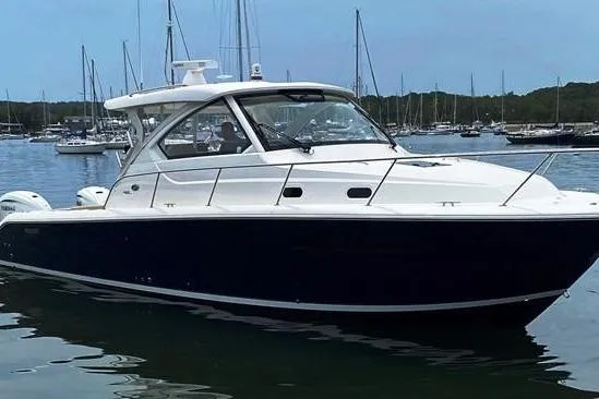 The Image of 2016 Pursuit OS 355 Offshore boat docked in marina, surrounded by sailboats. - 0