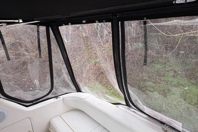 Slide: The Image of 1998 Sea Ray Sundancer 330 interior with clear enclosure, overlooking lush greenery. - 24