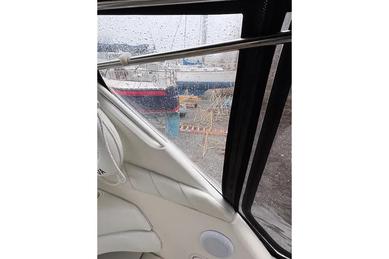 Slide: The Image of 1998 Sea Ray Sundancer 330 interior view with rainy window and docked boats outside. - 25