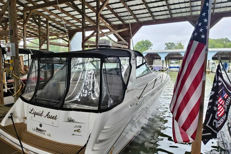 Slide: The Image of 1998 Sea Ray Sundancer 330 docked under a covered marina with American flag nearby. - 37