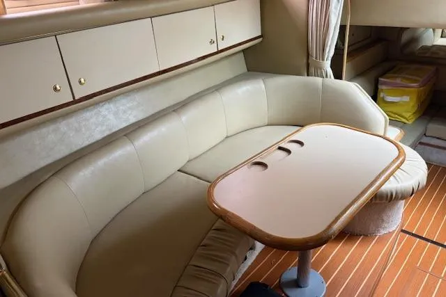 Slide: The Image of 1998 Sea Ray Sundancer 330 interior with beige leather seating and wooden table. - 9